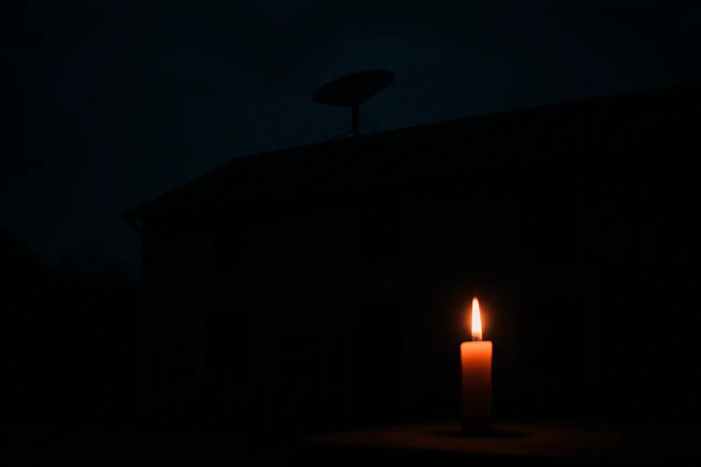 Dunkelheit mit Kerze und Starlink Antenne