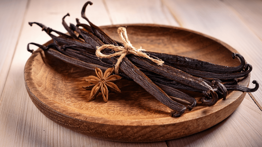Rustikale Holzplatte mit getrockneten Vanilleschoten und Sternanis als dekoratives Titelbild