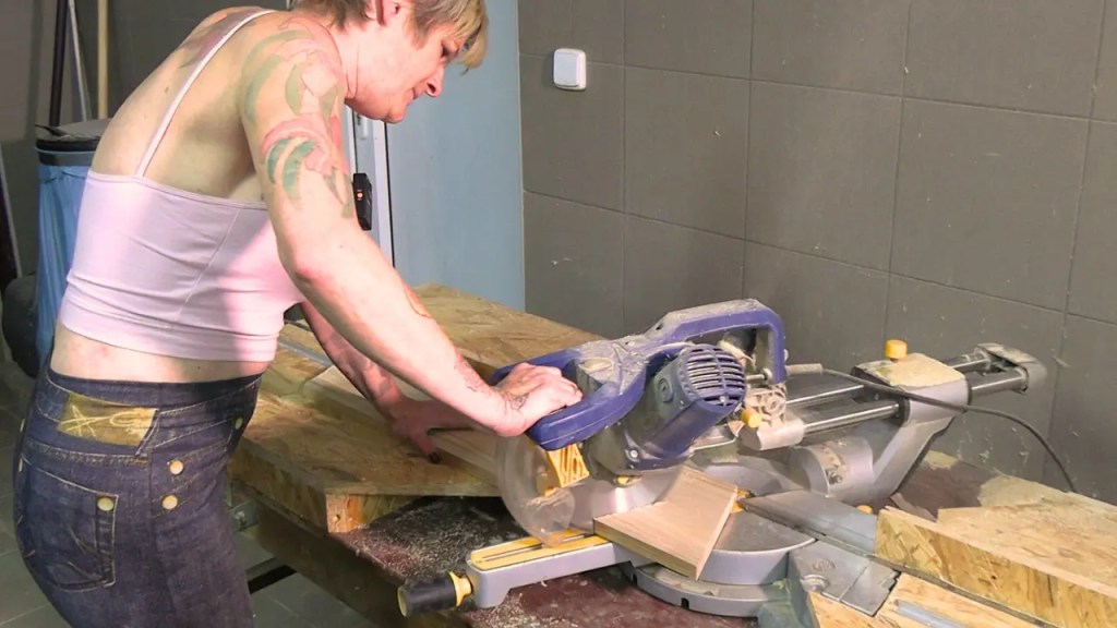Eine Person schneidet an einer Kappsäge ein Brett in passende Länge