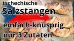 Frisch gebackene tschechische Rohlíky mit knuspriger Kruste auf Backpapier und Holzbrett, selbstgemachte Salzstangen aus Hefeteig ohne Industrieprodukte