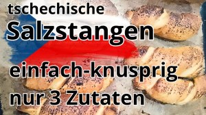 Frisch gebackene tschechische Rohlíky mit knuspriger Kruste auf Backpapier und Holzbrett, selbstgemachte Salzstangen aus Hefeteig ohne Industrieprodukte